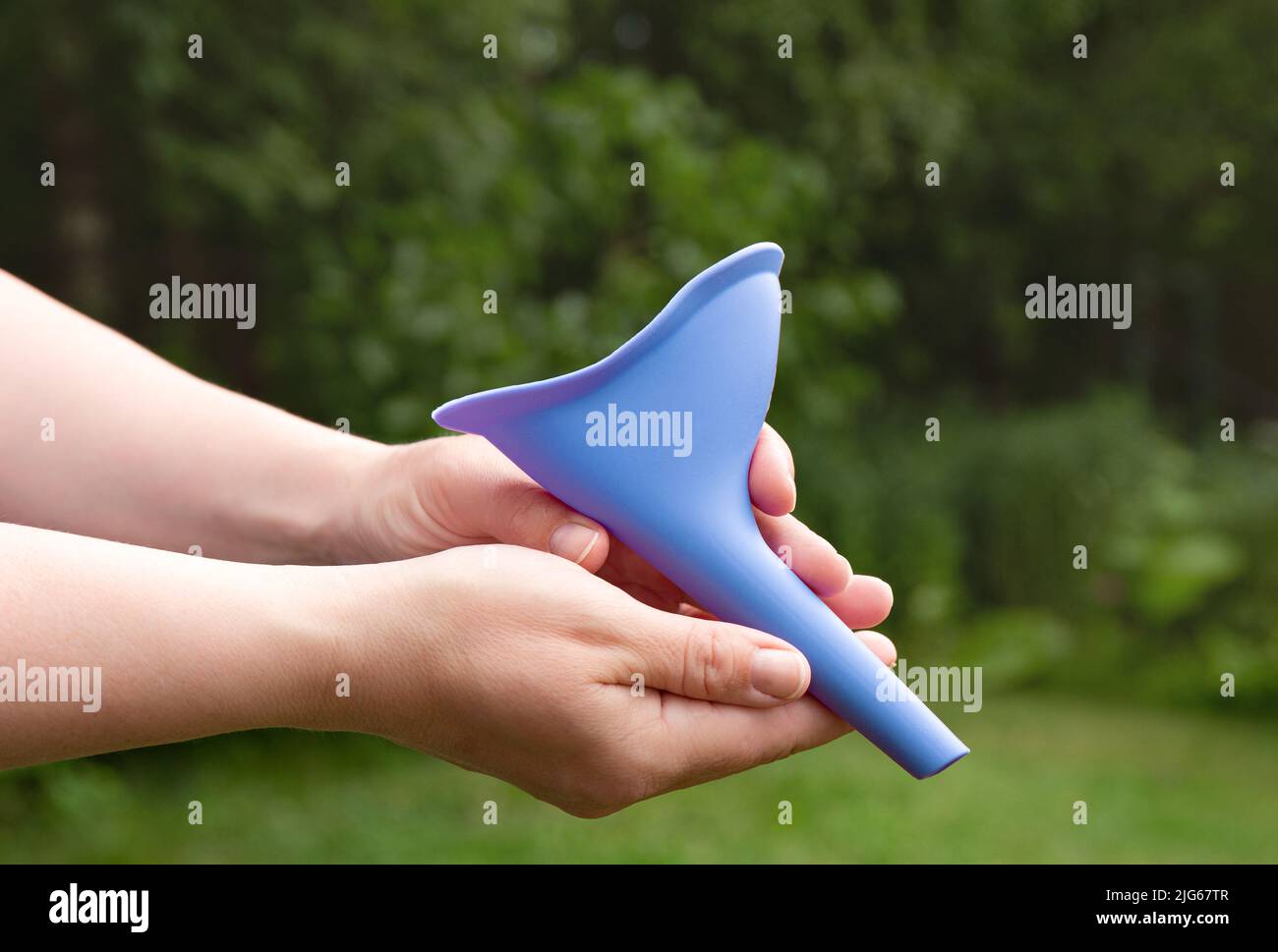 Device for women, pee funnel, to use while camping outdoors, helps urinating standing. Woman hands holding the tool. Stock Photo