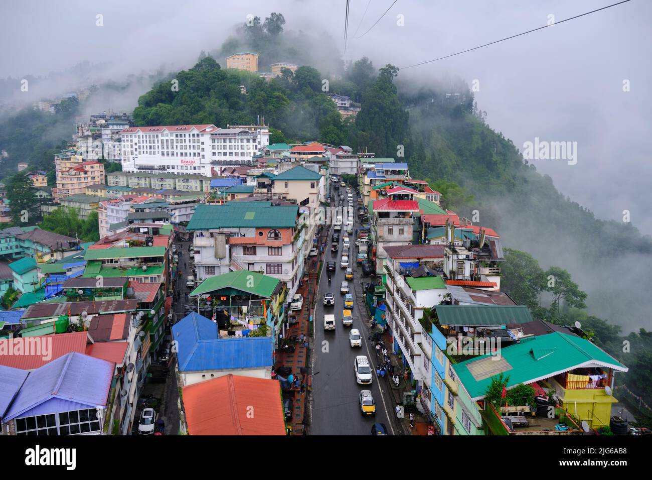 Gangtok, Sikkim - June 16 2022, Tourists enjoy a ropeway cable car ride over Gangtok city. Amazing aerial cityscape of Sikkim. covered in mist or fog. Stock Photo