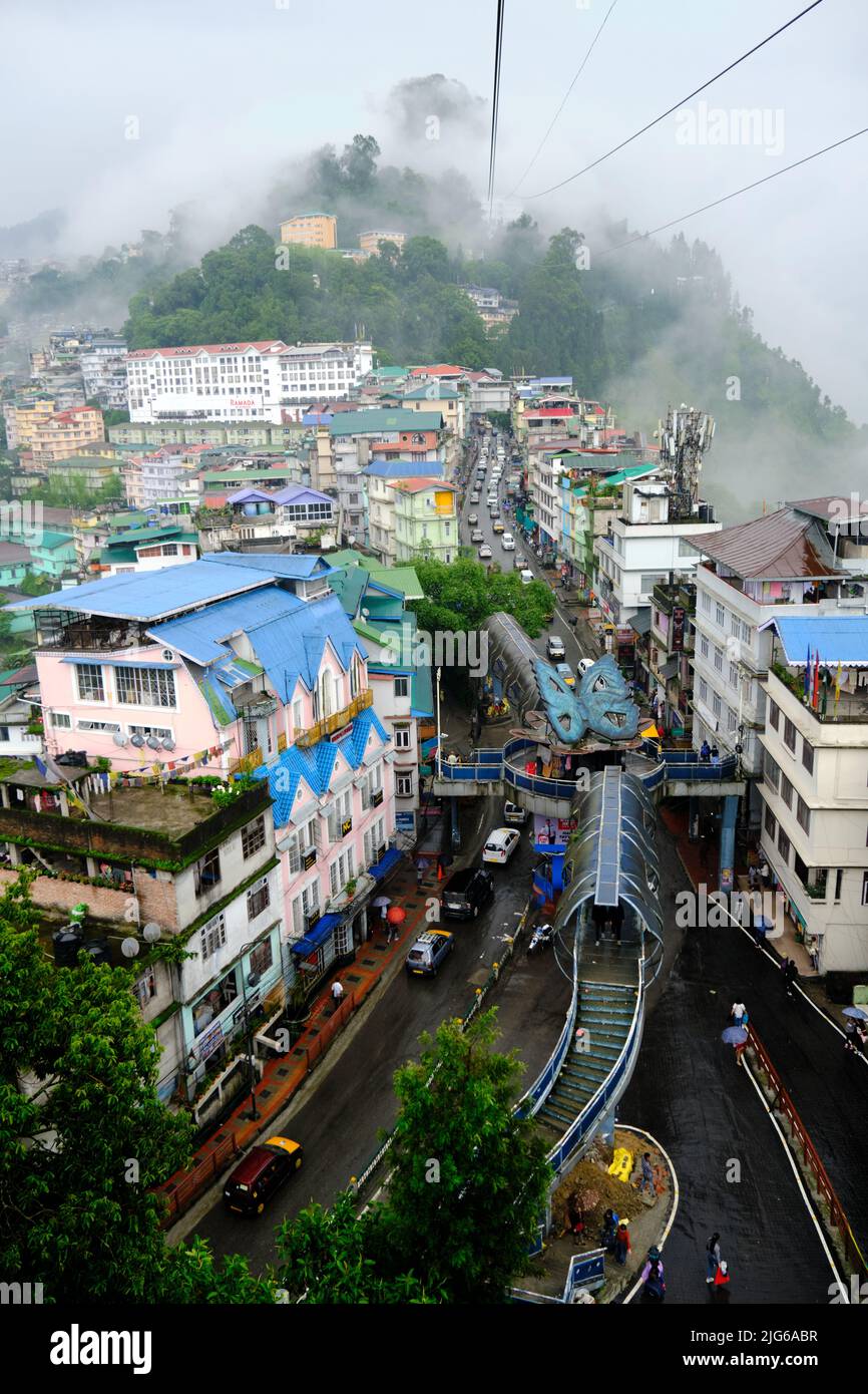 Gangtok, Sikkim - June 16 2022, Tourists enjoy a ropeway cable car ride over Gangtok city. Amazing aerial cityscape of Sikkim. covered in mist or fog. Stock Photo