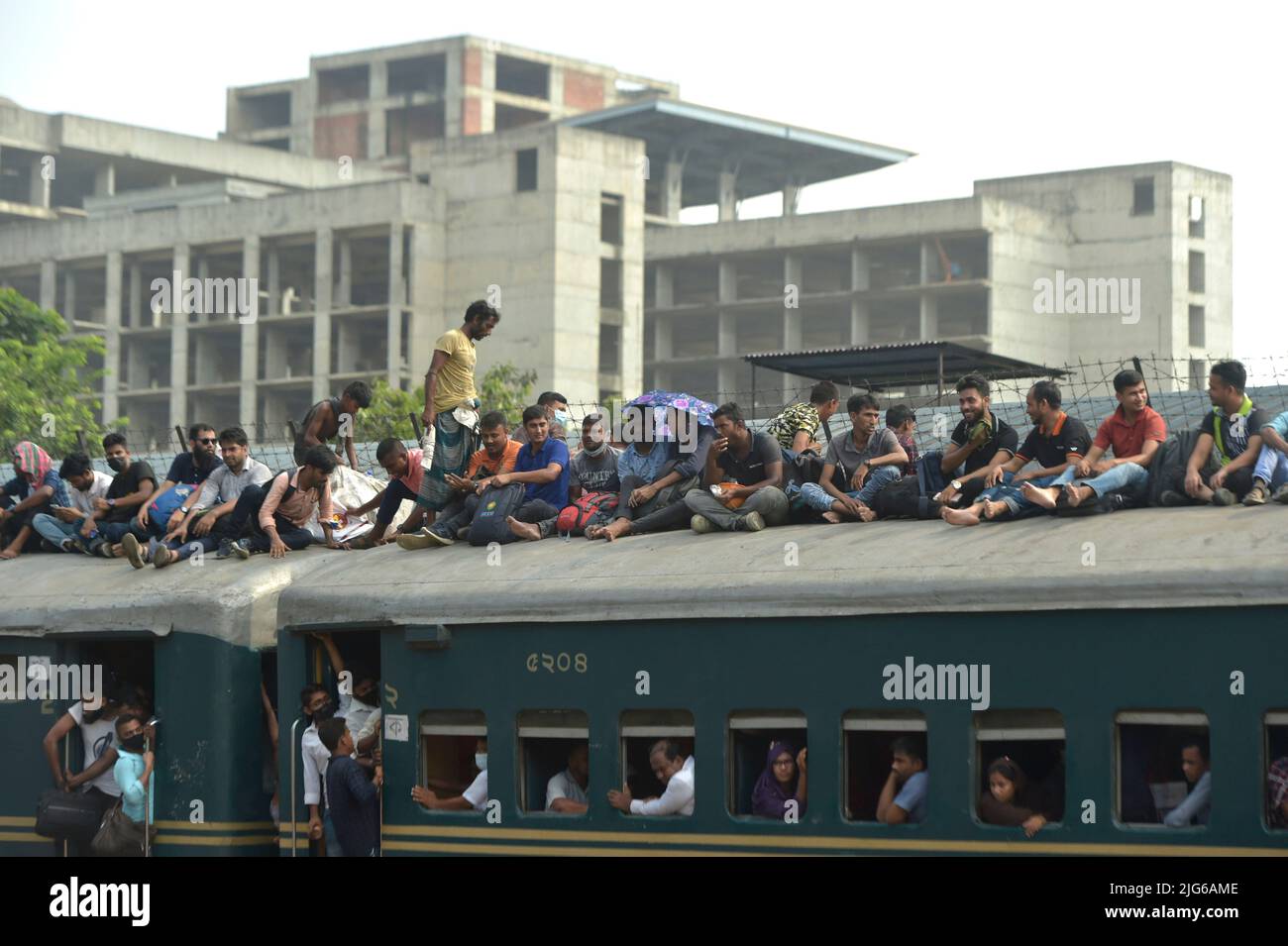 Dhaka. 8th July, 2022. Travelers sitting on the roof of a train leave a station in Dhaka, Bangladesh, July 7, 2022. As Eid al-Adha festival approaches, many people from Bangladesh capital Dhaka have streamed out of the city to join the festival with their kith and kin in village homes. Credit: Xinhua/Alamy Live News Stock Photo