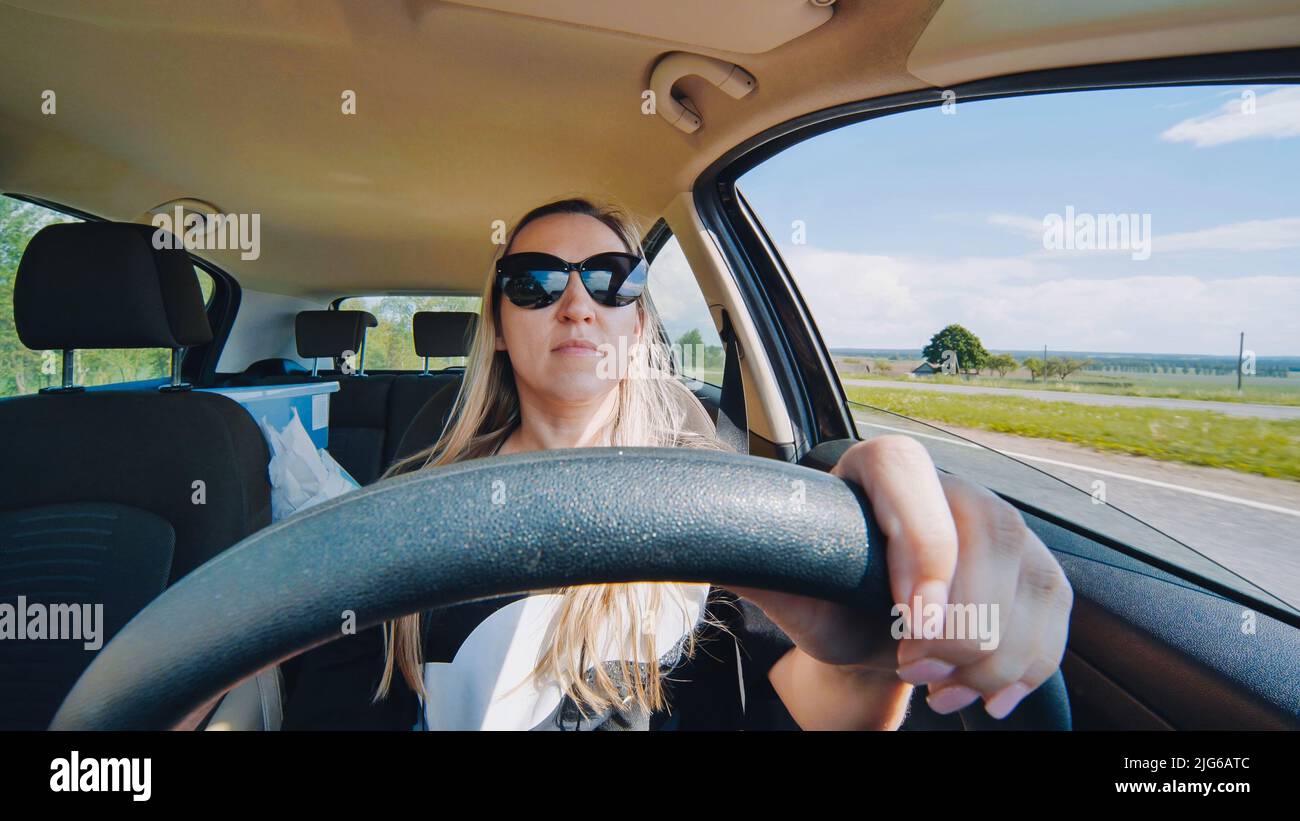 A young woman in a good mood behind the wheel of a car. Stock Photo