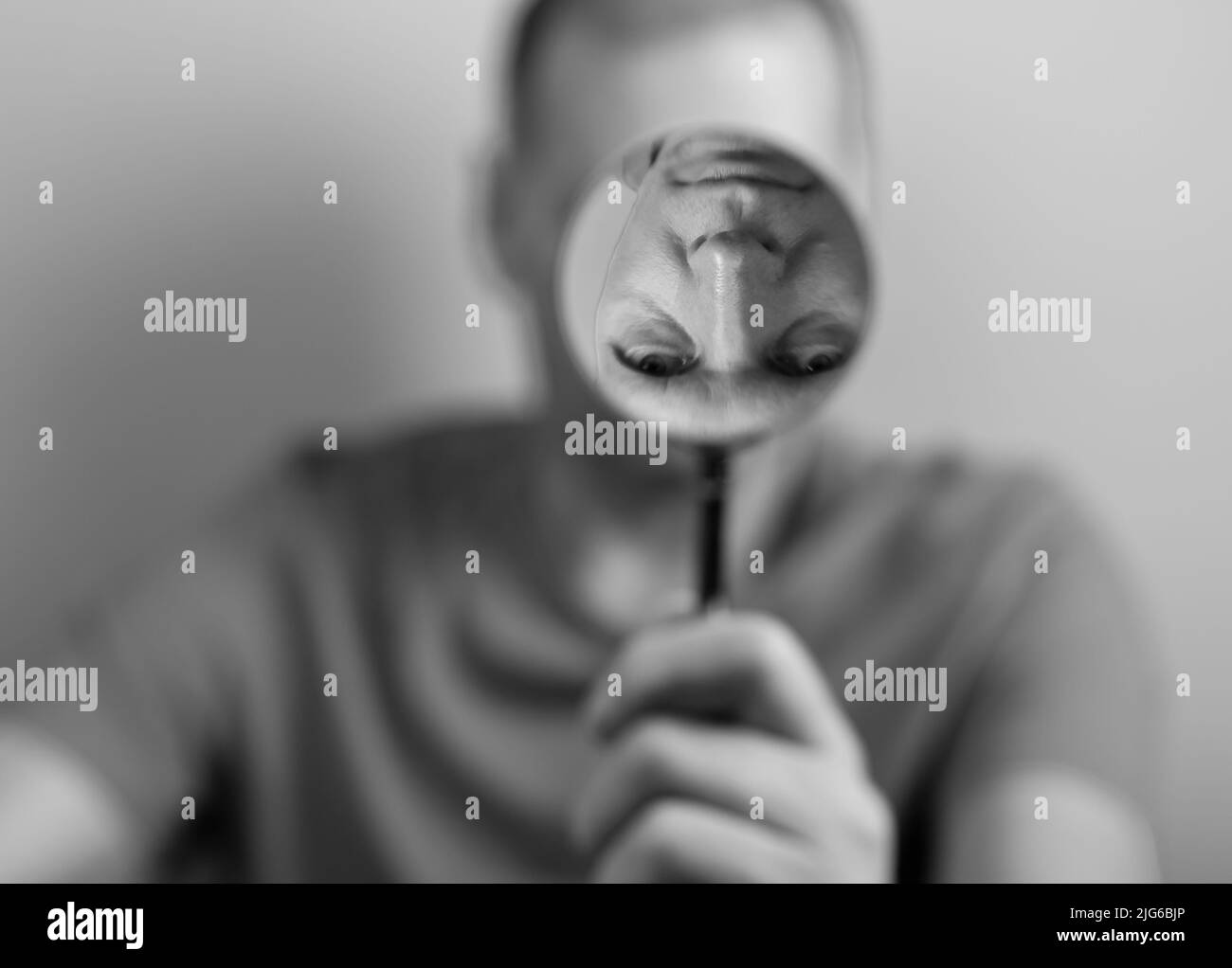 Psychology concept of distorted self perception. Man with magnifying glass and upside down fake reflection. High quality photo Stock Photo
