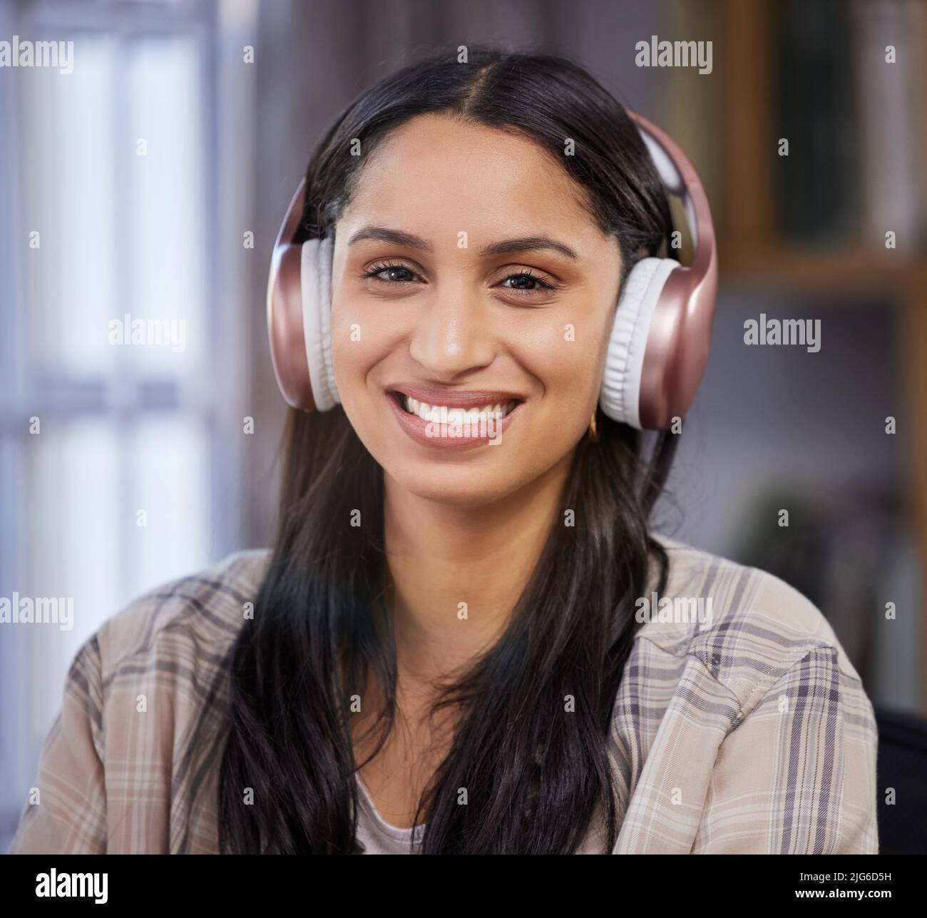 Content in my apartment. Shot of a young student using headphones while studying at home. Stock Photo