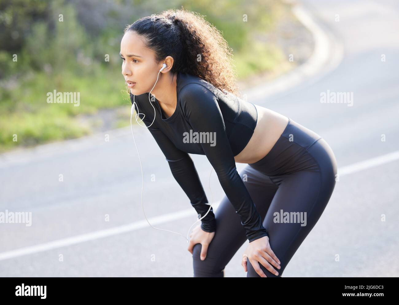Catch your breath. Shot of a beautiful young woman catching her breathe while having her morning run outside. Stock Photo