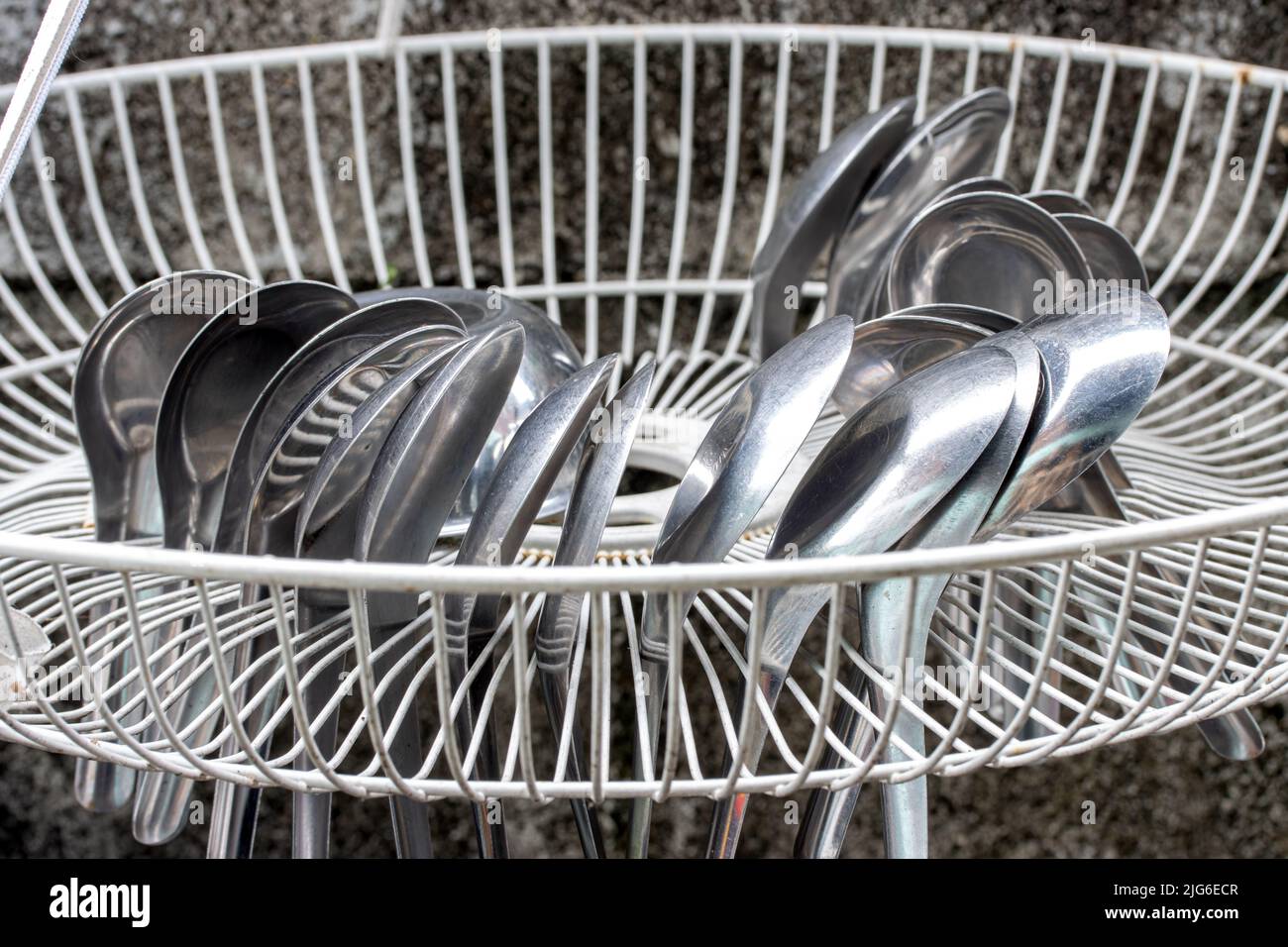 Aluminum spoons are dried in a grate drip tray hang on the wall Stock