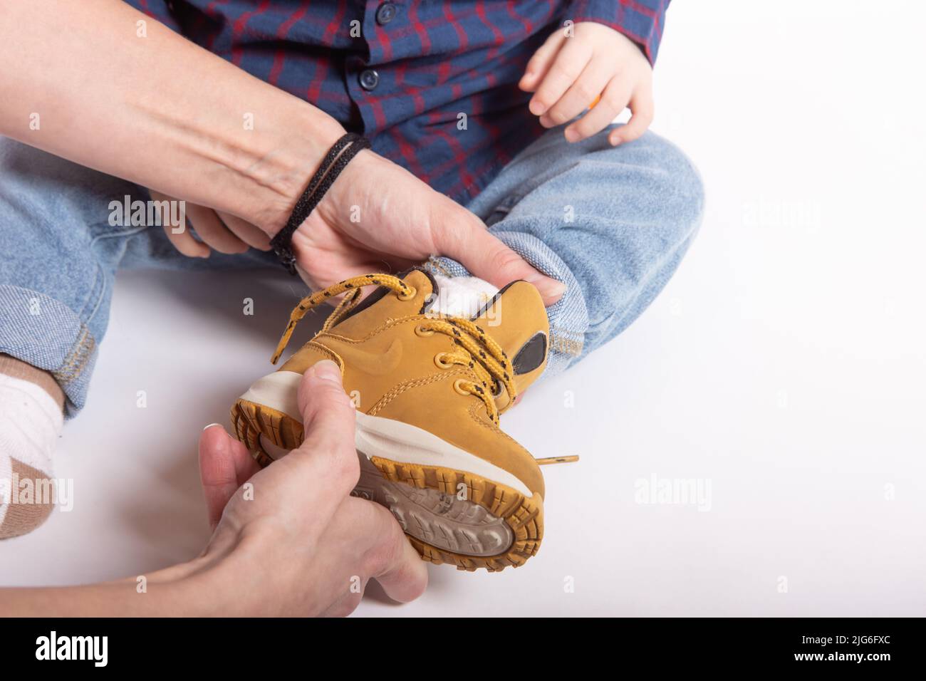 A mother puts shoes on little son's feet Stock Photo - Alamy