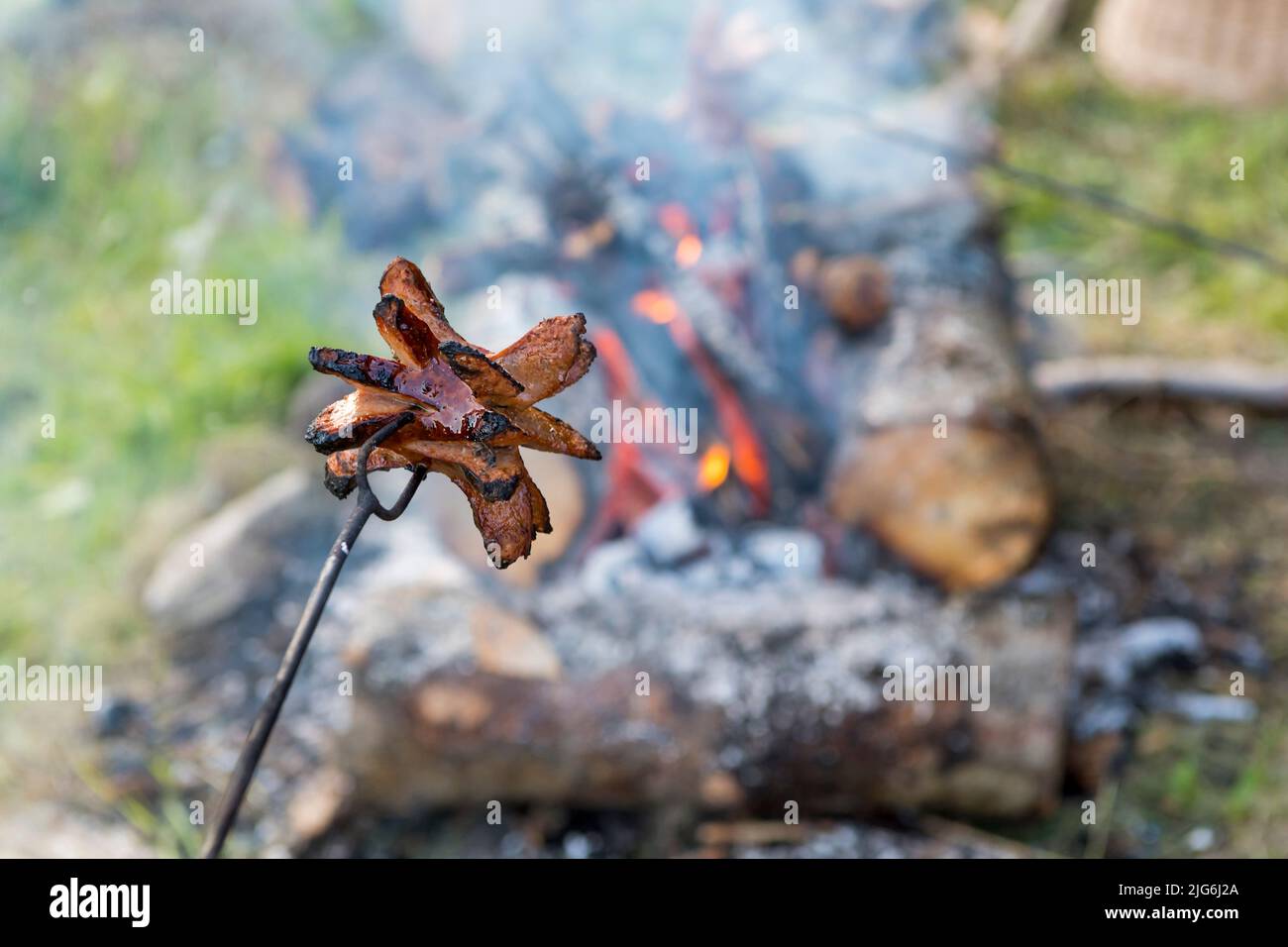 sausage or banger above campfire Stock Photo