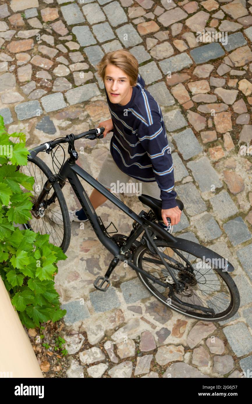 shot of boy on cobblestones street with bicycle from above Stock Photo