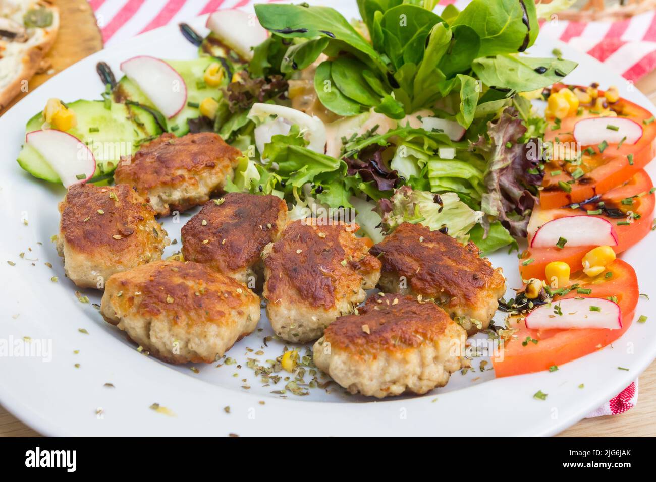 Traditional german small meatballs (frikadelle) served with salad and tomato on a white plate Stock Photo