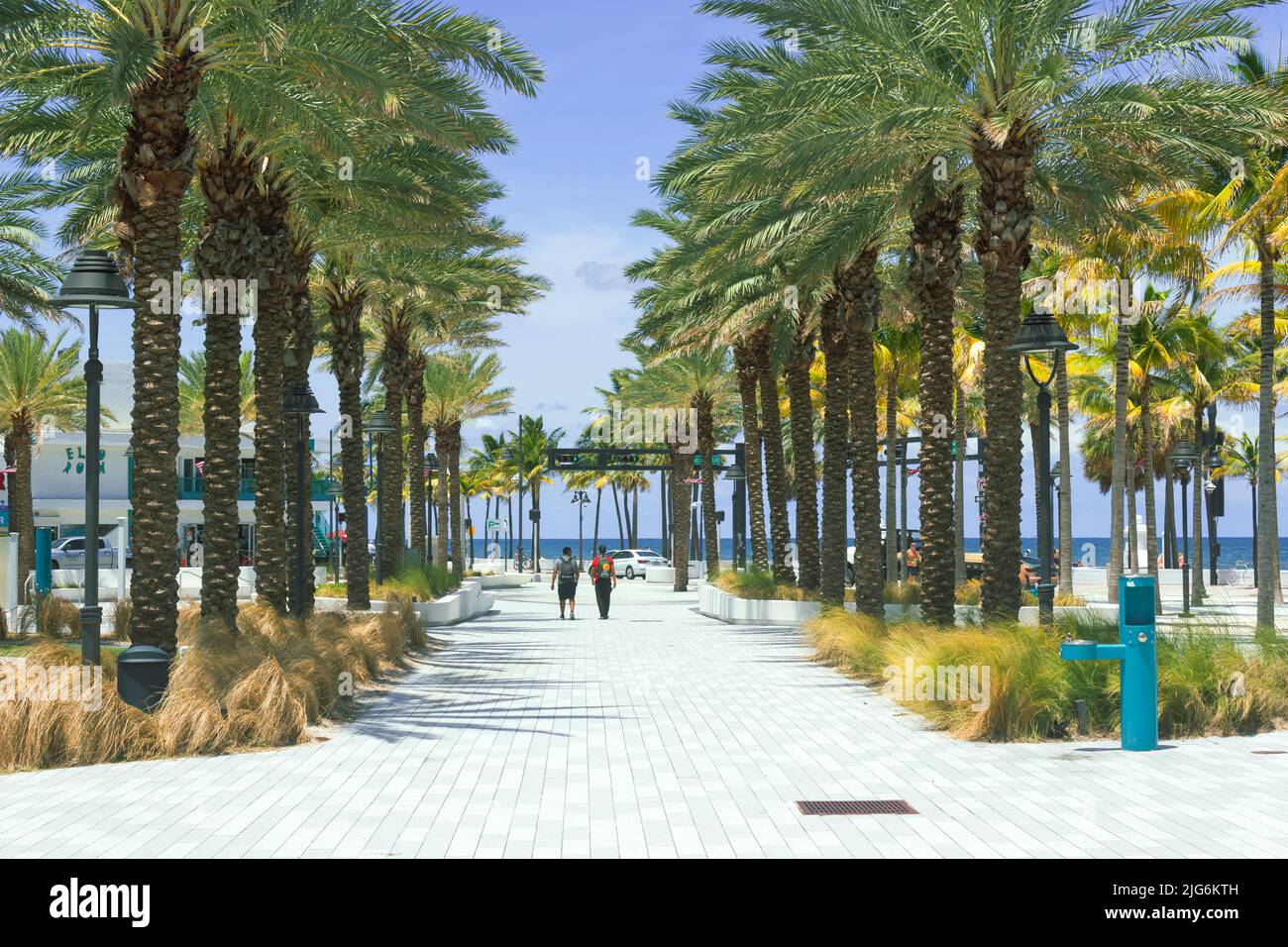 Two people walking on a pathway lined with palm trees at Beach Las Olas Oceanside Beach Fort Lauderdale Stock Photo