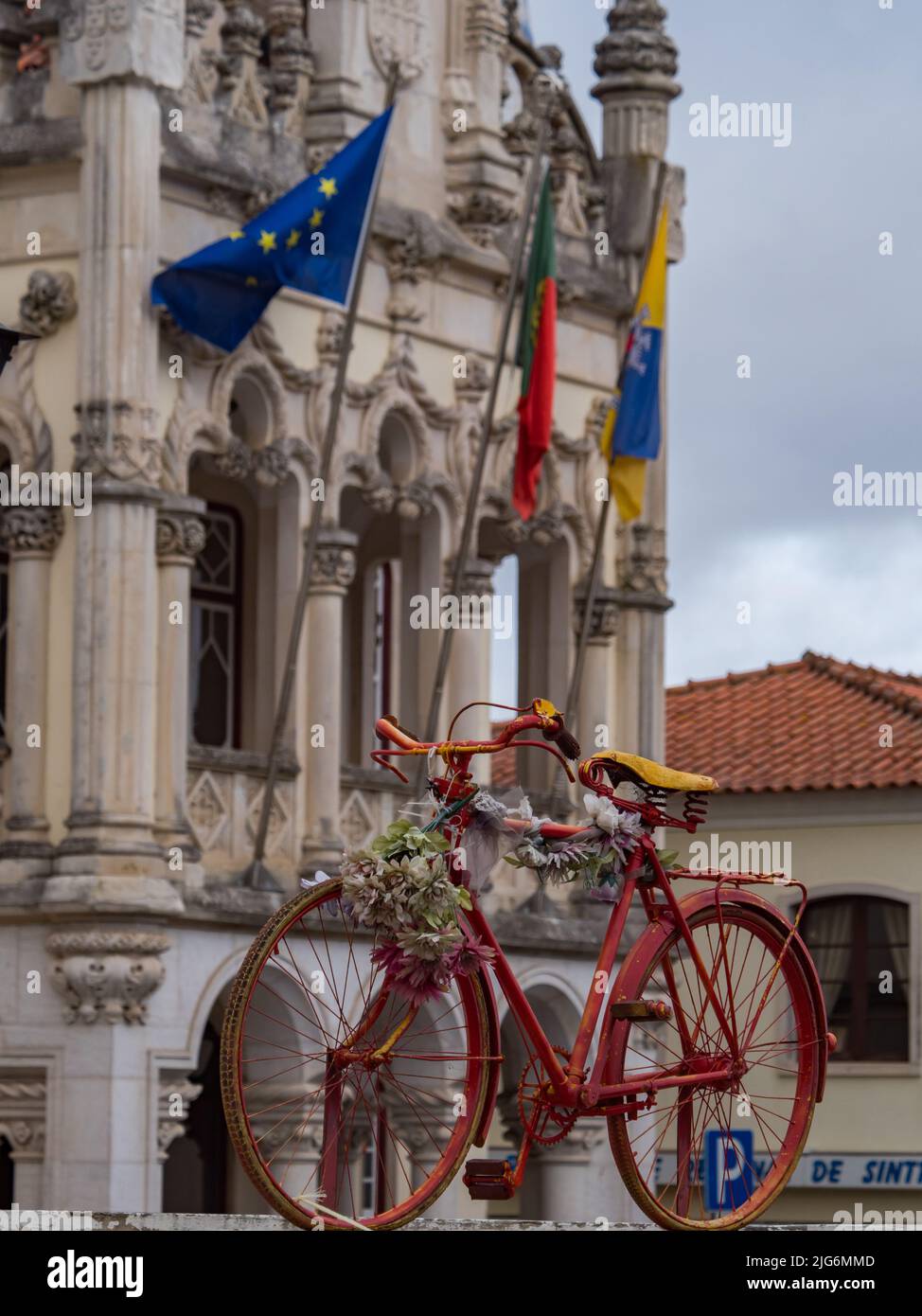Old, red bike on the fence and a beautiful Town Hall building with the flags of Europe, Portugal and Sintra in the background (Câmara Municipal de Sin Stock Photo