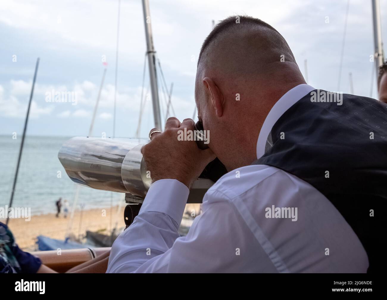 A middle aged man using a telescope to look out to sea Stock Photo