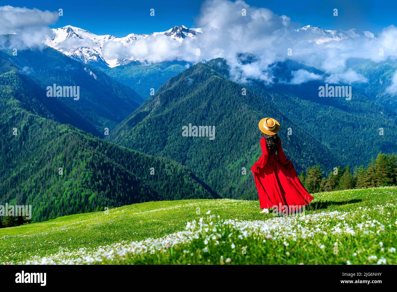 Tourist enjoy view of green pasture and flowers near snow mountain in Georgia. Stock Photo