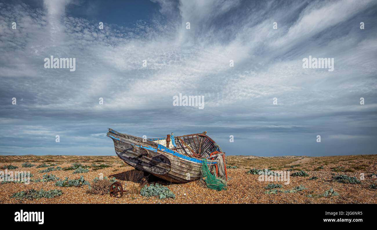 On the shingle beach of Dungeness Headland in Kent are several old, abondoned fishing boats Stock Photo