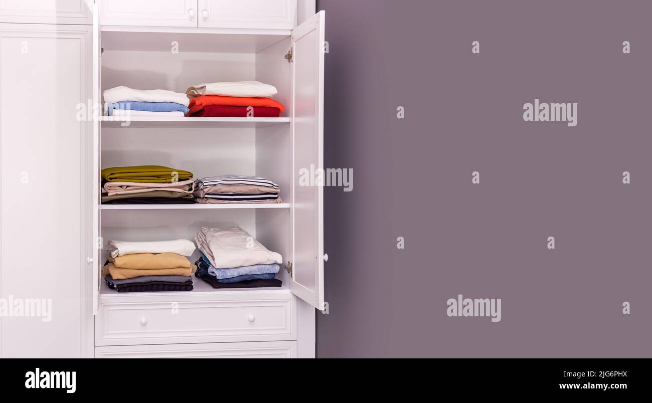 white closet in which things are neatly folded. Copy space, gray background Stock Photo
