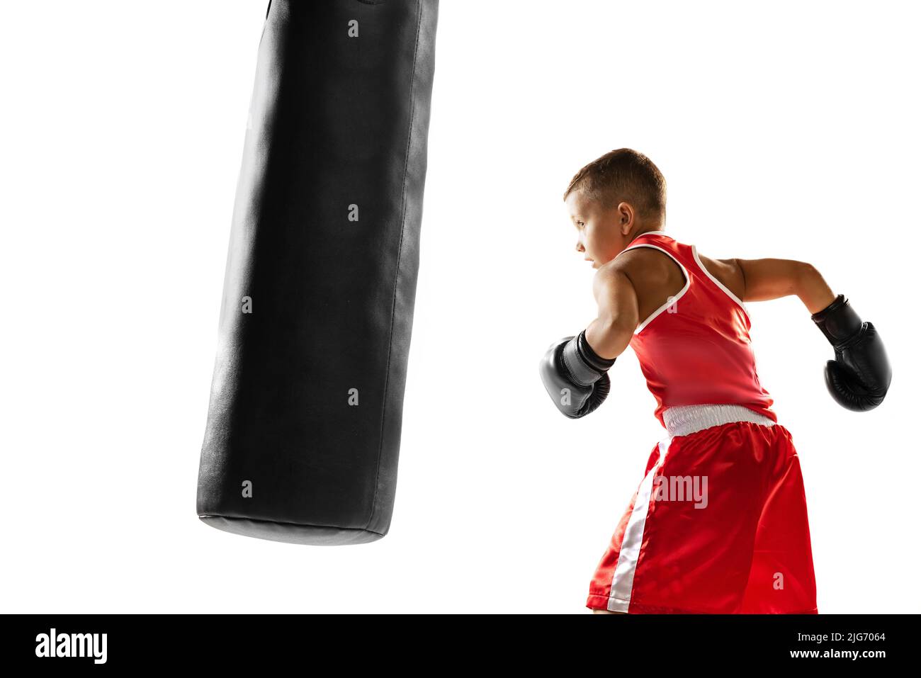 Kid practicing punch on punching bag. Beginner boxer, sportive boy