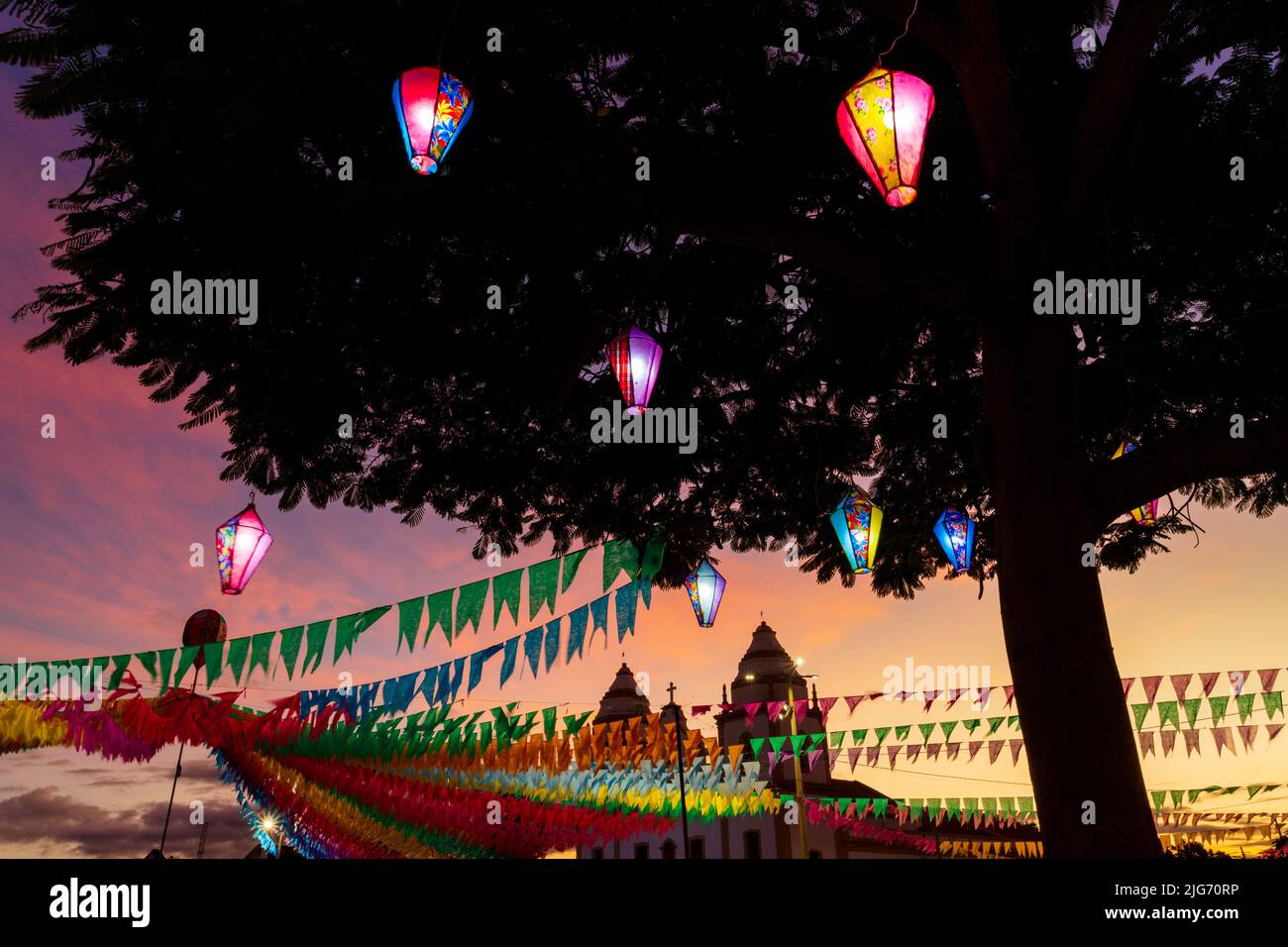 festa junina decoration with illuminated decorative balloon and colorful flags in front of são joão church Stock Photo