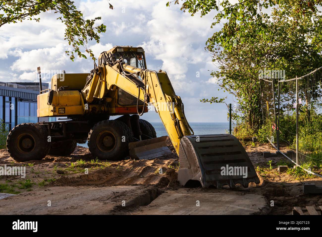 Yellow excavator standing on a seashore on a sunny day Stock Photo - Alamy