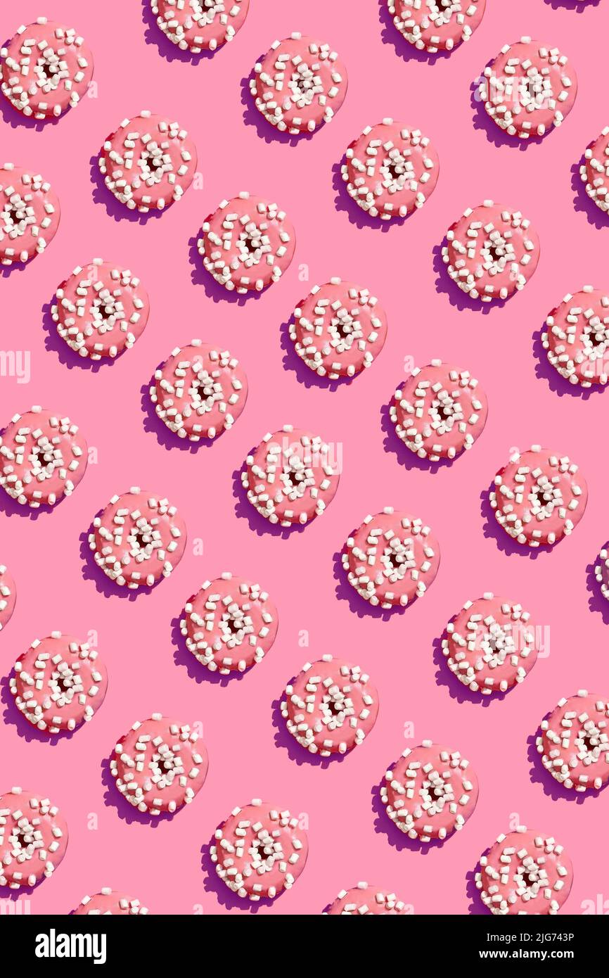 Food design with tasty pink glazed donut on coral pink pastel background top view pattern Stock Photo