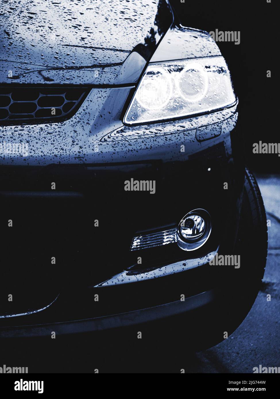 half front of wet black powerful car, night or blue hour light-shade Stock Photo