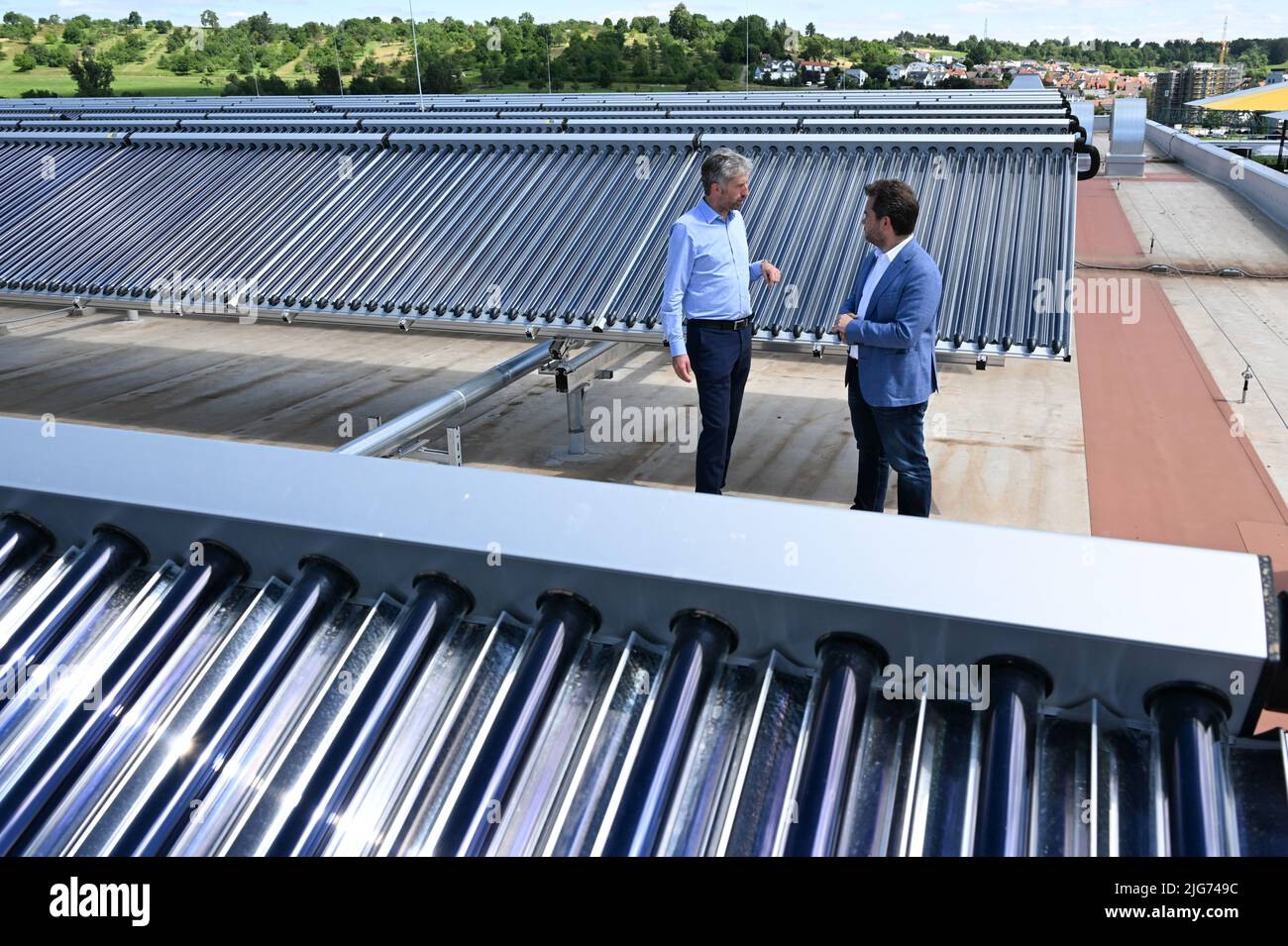 Dettenhausen, Germany. 08th July, 2022. Boris Palmer (l), Mayor of Tübingen, and Moritz Ritter, former Managing Director and Chairman of the Advisory Board of Ritter Energie und Umwelttechnik, stand by a new rooftop solar thermal system during a presentation meeting. Chocolate manufacturer Alfred Ritter and Tübingen's municipal utility have conceived a project for the energy and heat turnaround. The focus is on what is currently Germany's largest rooftop solar thermal system, which Ritter Sport has installed on the roof of its new warehouse building. Credit: Bernd Weißbrod/dpa/Alamy Live News Stock Photo