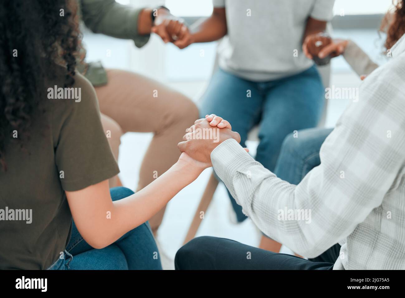 Lets keep each other motivated. Cropped shot of an unrecognisable group of people sitting together and holding hands during prayer. Stock Photo