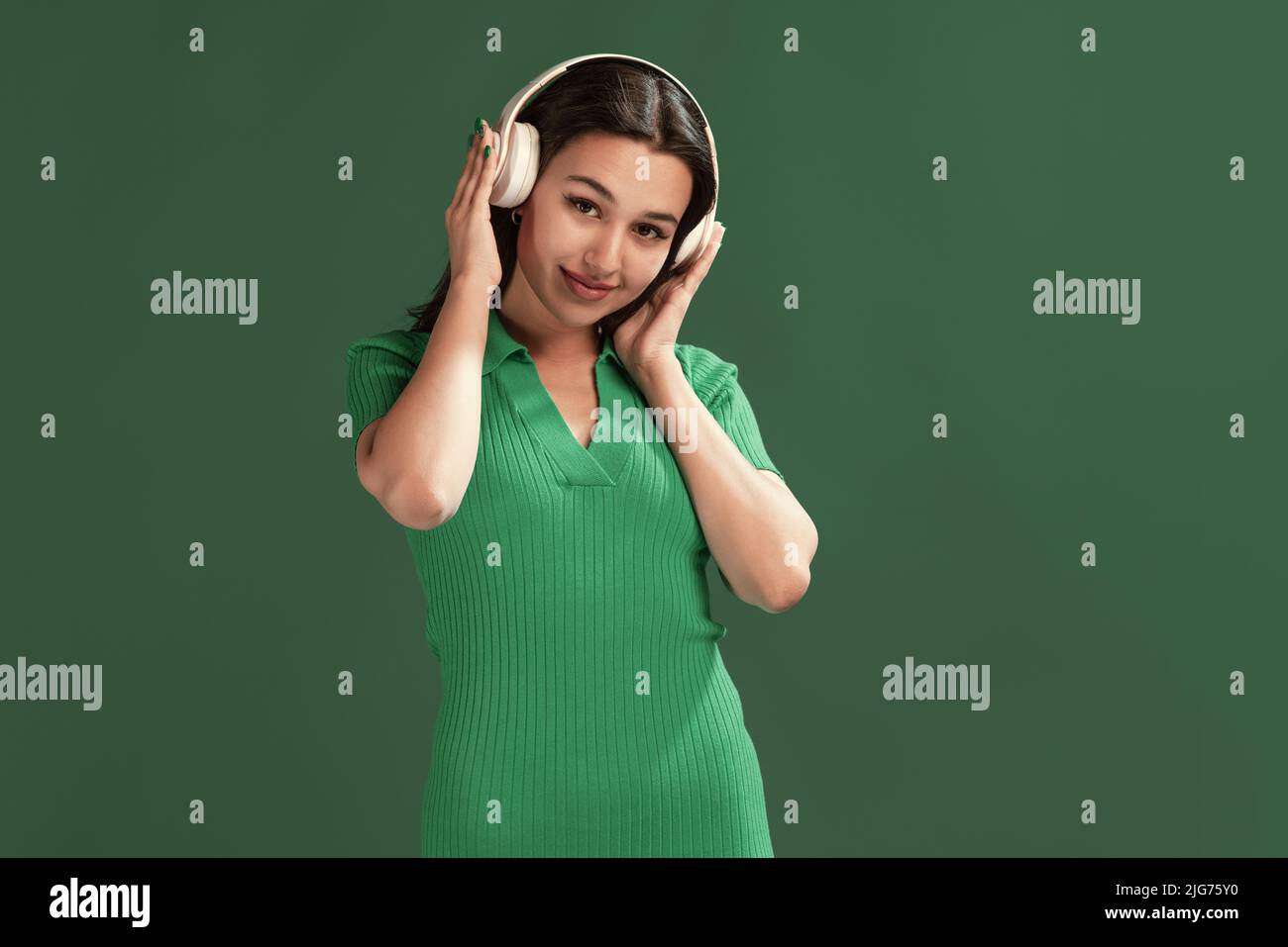 Portrait of beautiful young girl listening to music in headphones ...