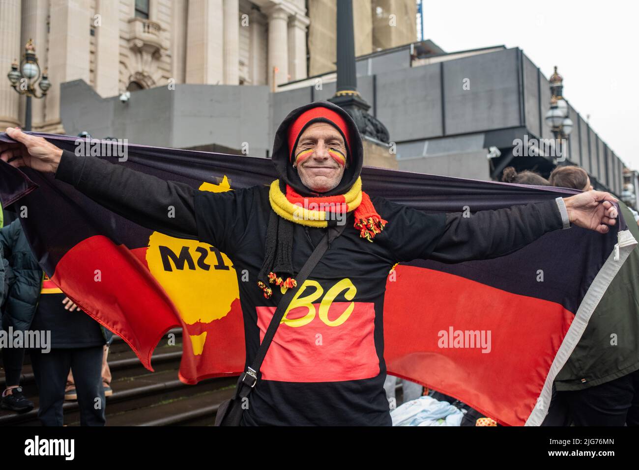 Melbourne, Australia. 8th July 2022. A man poses with the Indigenous flag at the NAIDOC week march, outside parliament house. Credit: Jay Kogler/Alamy Live News Stock Photo