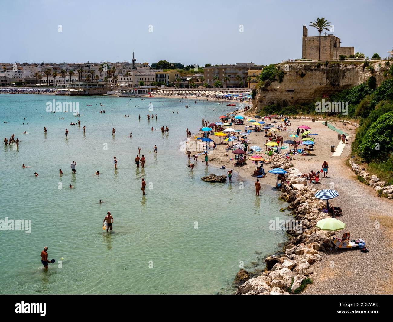 Panoramic view of the Bay of Otranto during the summer with bathers enjoying the turquoise water with the skyline of Otranto in the distance Stock Photo
