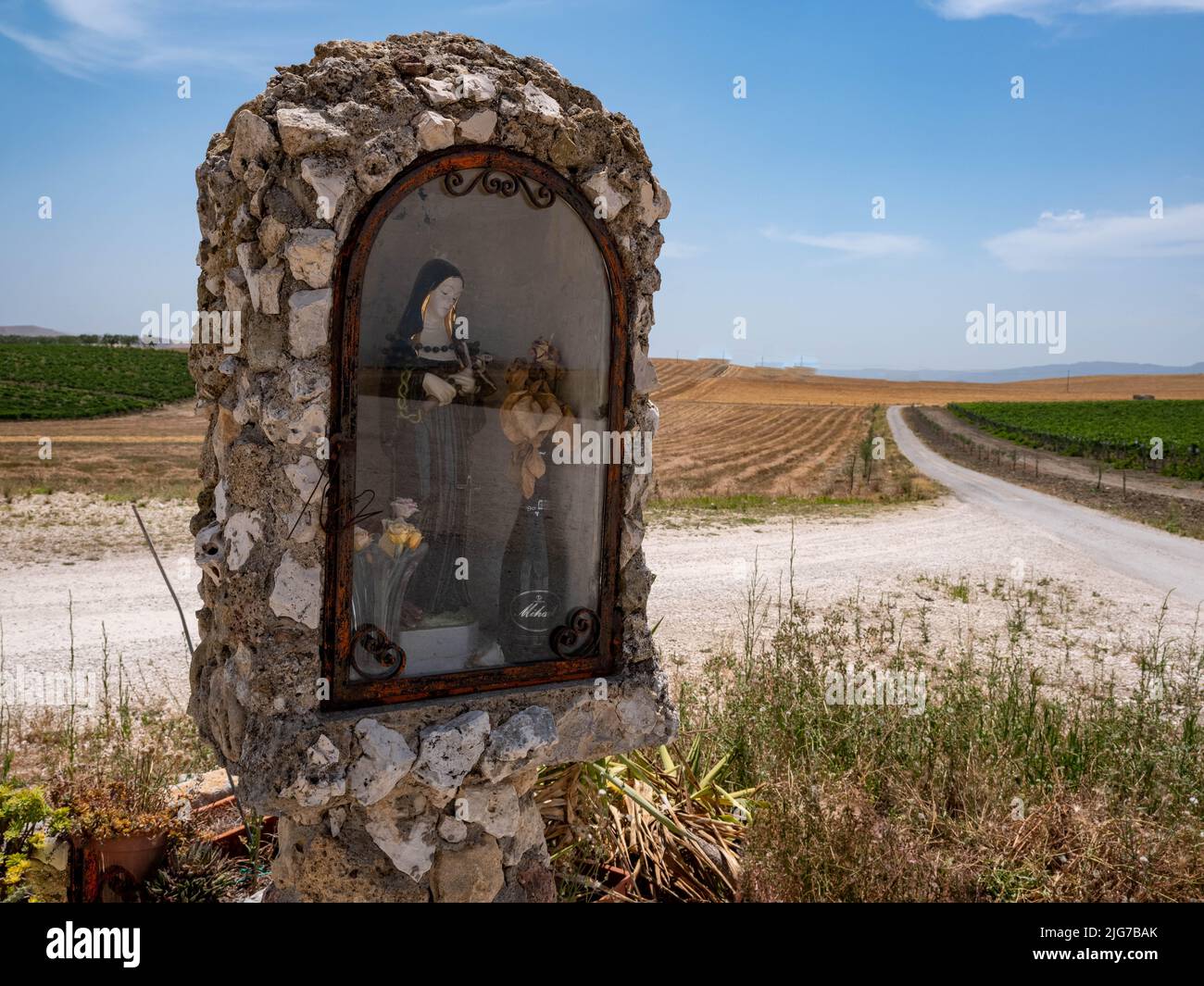 Roadside devotional mini-chapel made of stones and featuring the Virgin Mary or a Saint behind a glass door near Matera, Italy Stock Photo