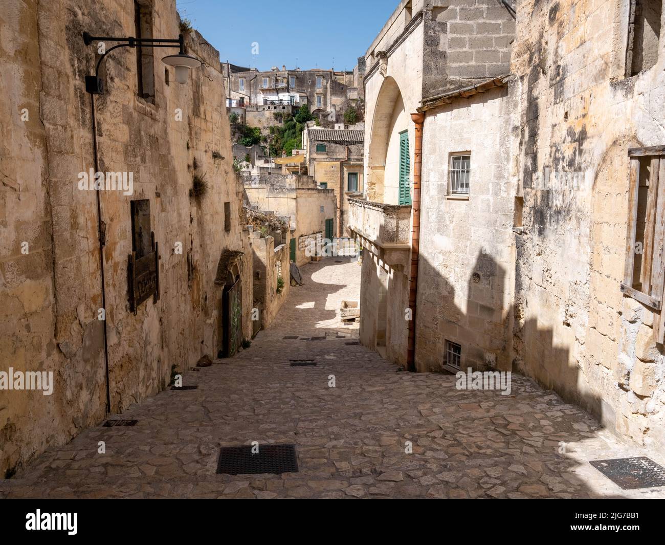 Steps heading uphill in the Old Town or Sassi of Matera, Italy with the silhouette of sculptures of human forms at the top of the stairs Stock Photo