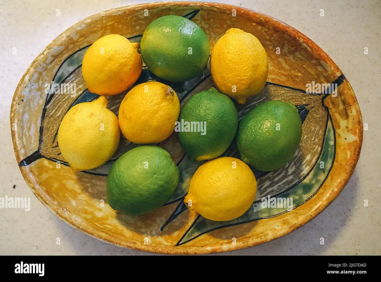 Citrus fruit sit in a patterned wooden oval bowl. Stock Photo