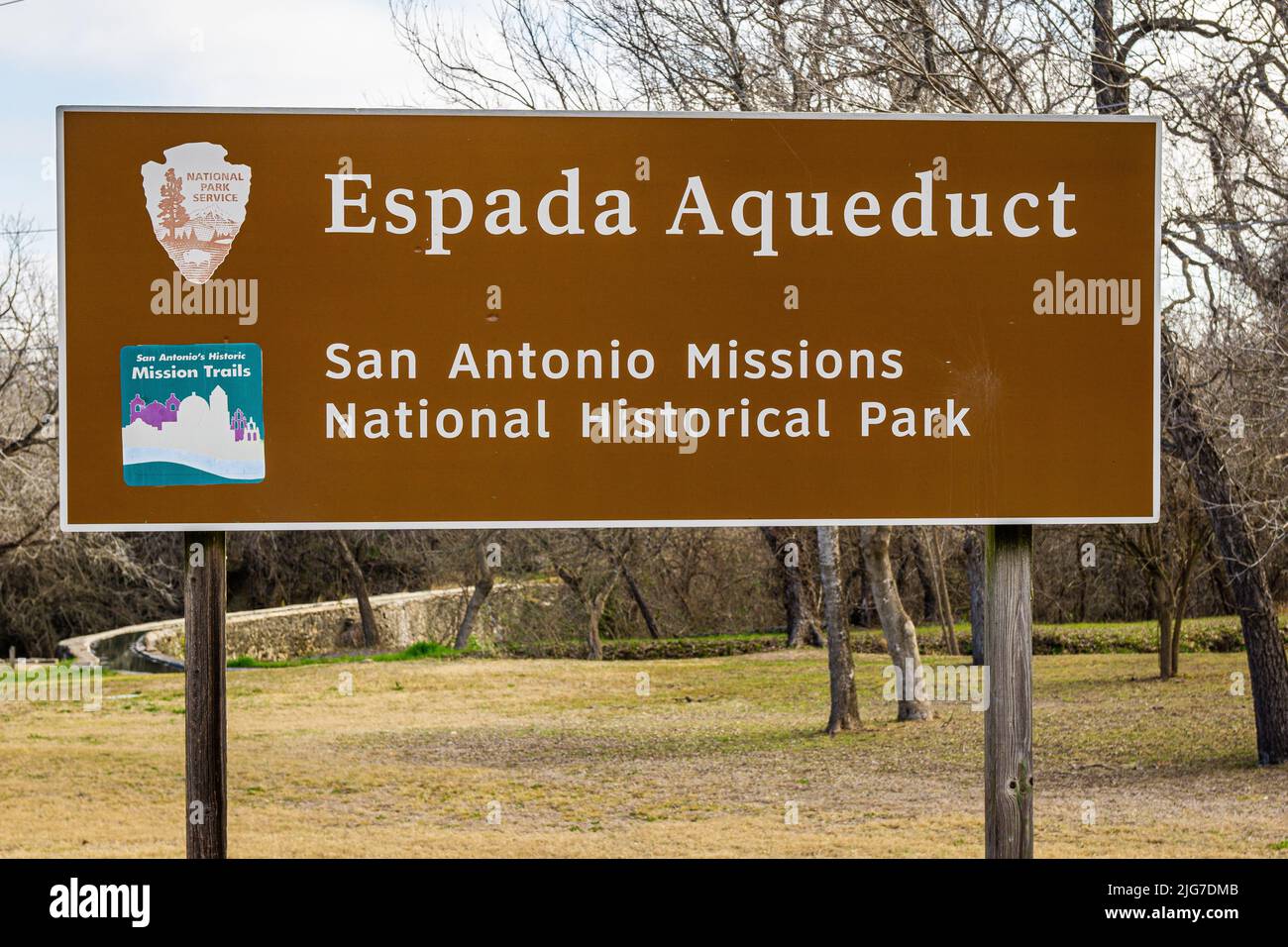 Brown National Park Service Sign is posted at the Espada Aqueduct, part of the San Antonio Missions National Historical Park in Texas. Stock Photo