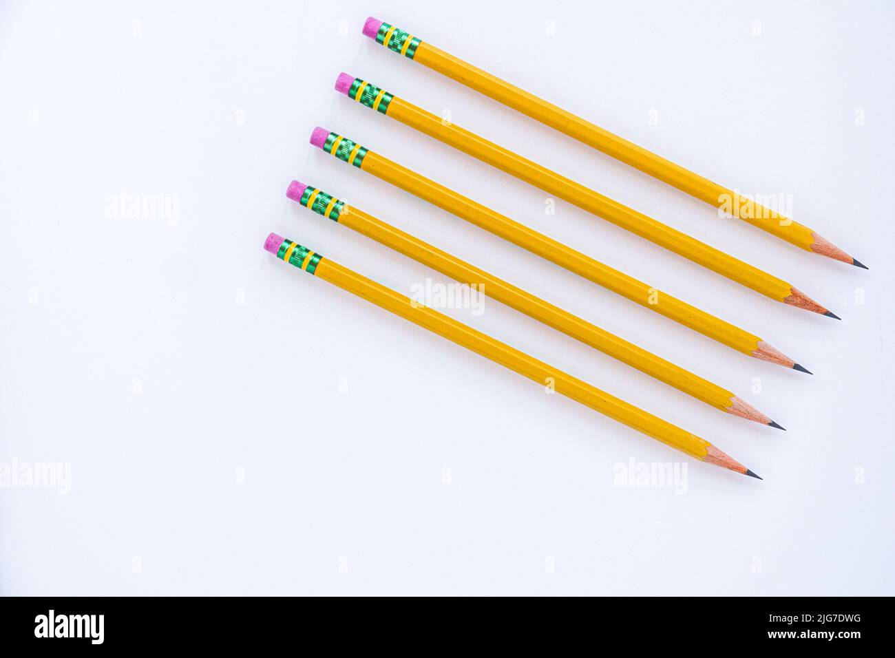 Negative space is utilized with five sharp pencils lined up on a white sheet of paper at an angle. Stock Photo
