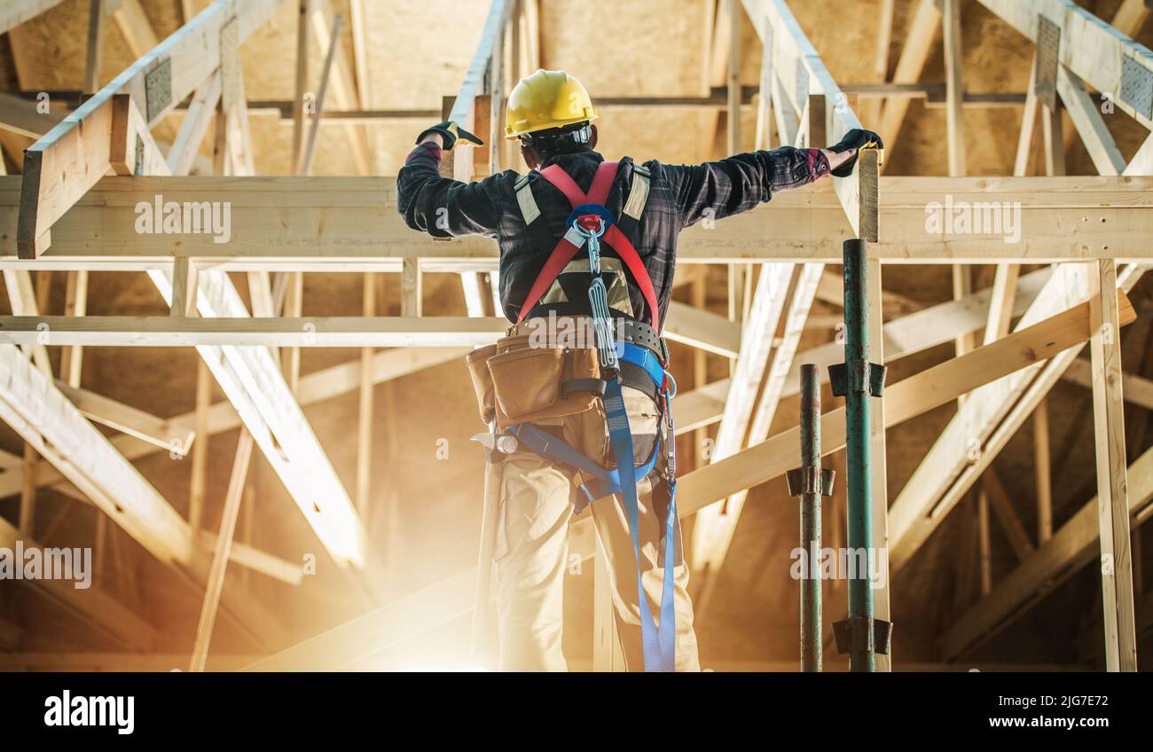Skeleton House Frame Construction Worker Wearing Safety Harness Staying in Front on the Building and Preparing Himself For the Job. Stock Photo