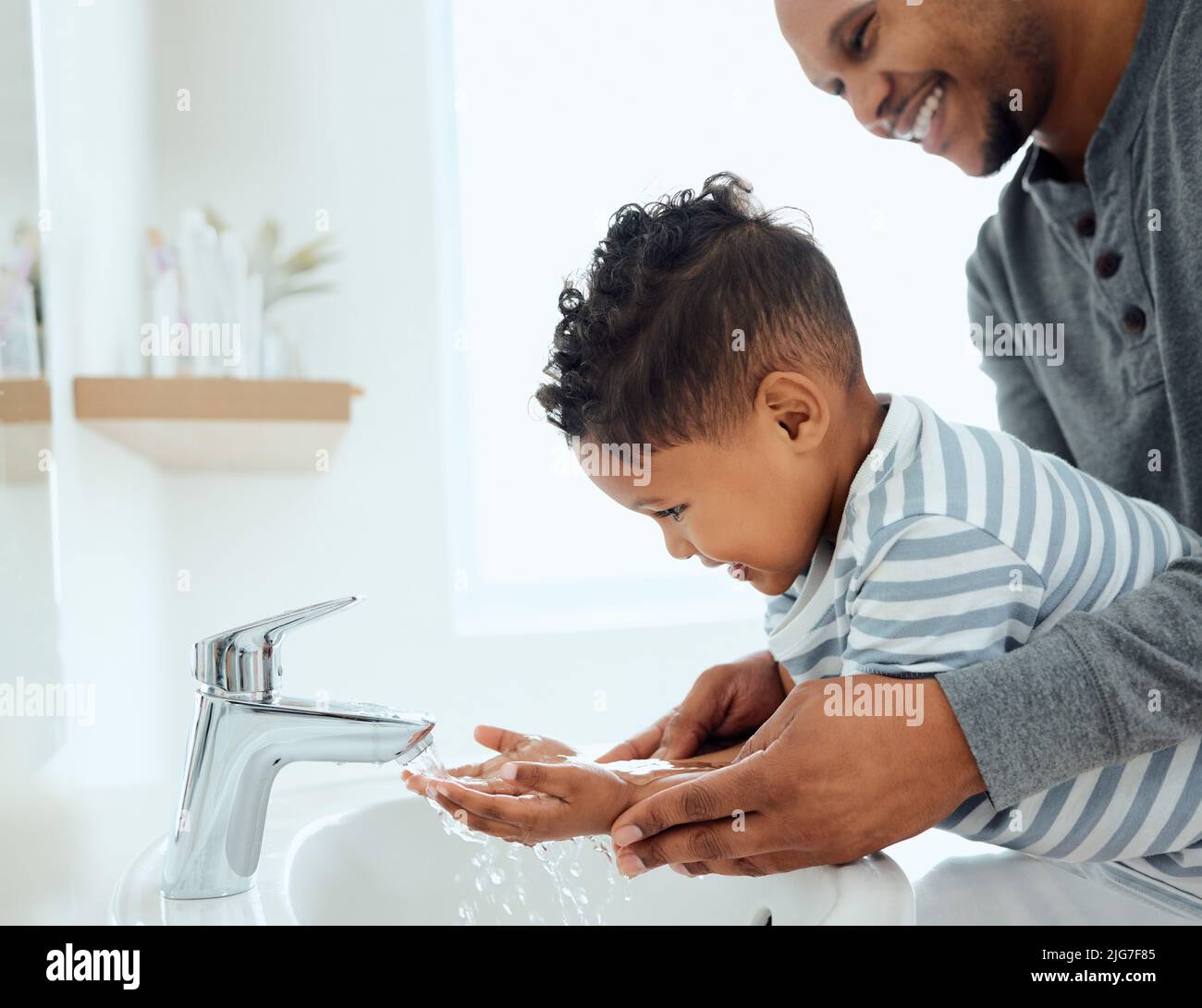 Wash them thoroughly. Shot of an adorable little boy washing his hands with the help of his father at home. Stock Photo