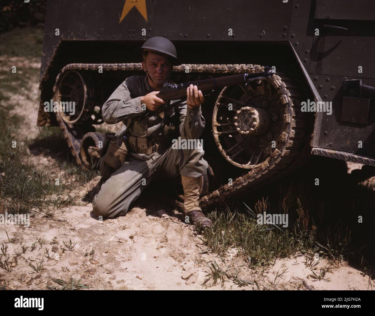 A young soldier of the armored forces holds and sights his Garand rifle like an old timer, Fort Knox, Ky. He likes the piece for its fine firing qualities and its rugged, dependable mechanism. Infantryman with halftrack. Stock Photo