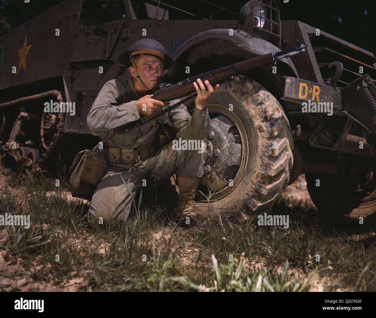 Infantryman with halftrack, a young soldier of the armed forces, holds and sights his Garand rifle like an old timer, Fort Knox, Ky. He likes the piece for its fine firing qualities and its rugged, dependable mechanism. Stock Photo