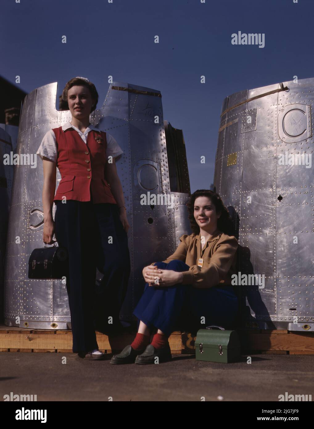 Two assembly line workers at the Long Beach, Calif., plant of Douglas Aircraft Company enjoy a well-earned lunch period, Long Beach, Calif. Nacelle parts of a heavy bomber form the background. Stock Photo