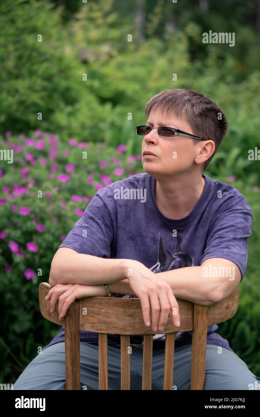 Caucasian woman in glasses sitting on the chair outdoor portrait Stock Photo