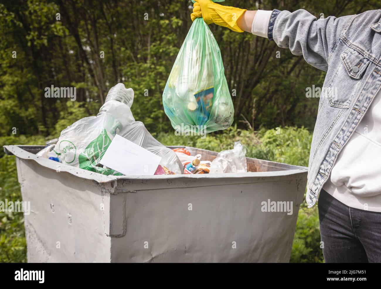 Throwing garbage into a trash can. Closeup of a hand holding a garbage bag over a dustbin Stock