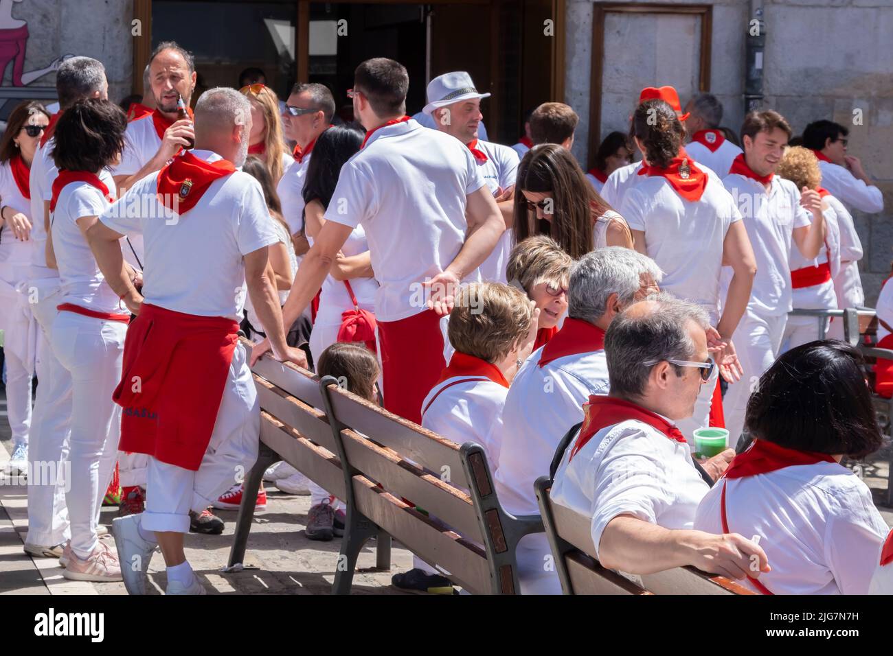 people in the street enjoying the atmosphere of the San Fermin festival in traditional white and red clothing with red necktie. July 07 2022. Pamplona Stock Photo