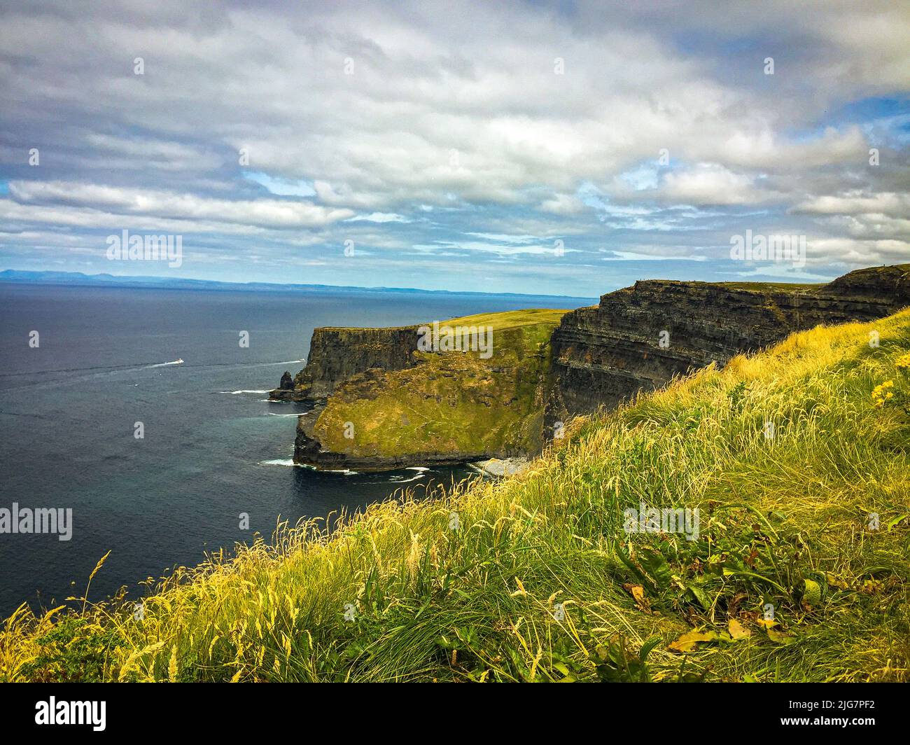 A beautiful view of the Cliffs of Moher above the sea under a cloudy sky Stock Photo