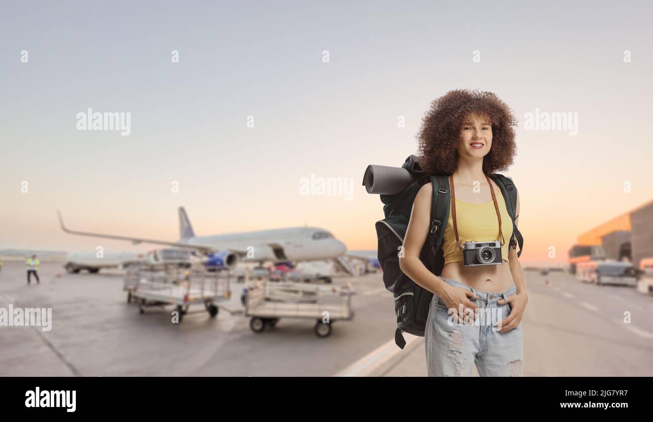 Young female traveler with a backpack standing on an airport apron Stock Photo
