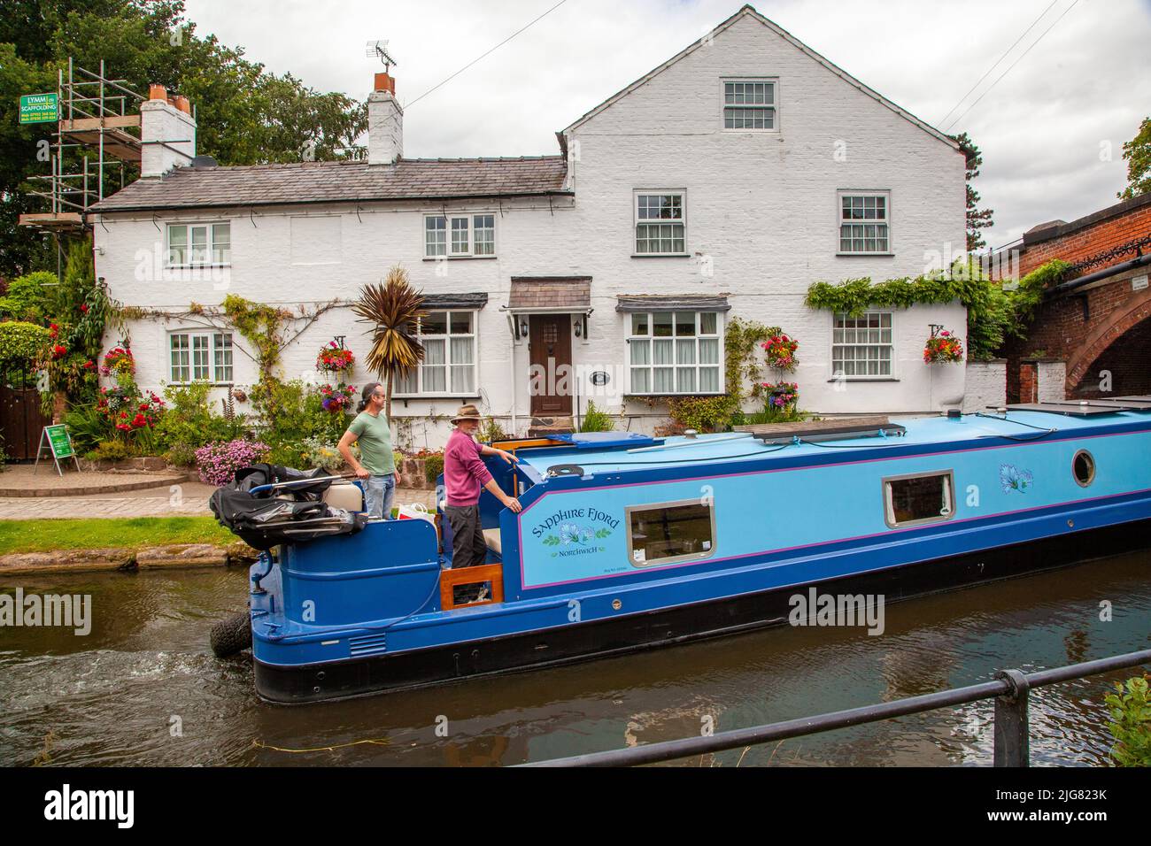 Canal narrowboat passing through the Cheshire village of Lymm on the Bridgewater canal Stock Photo