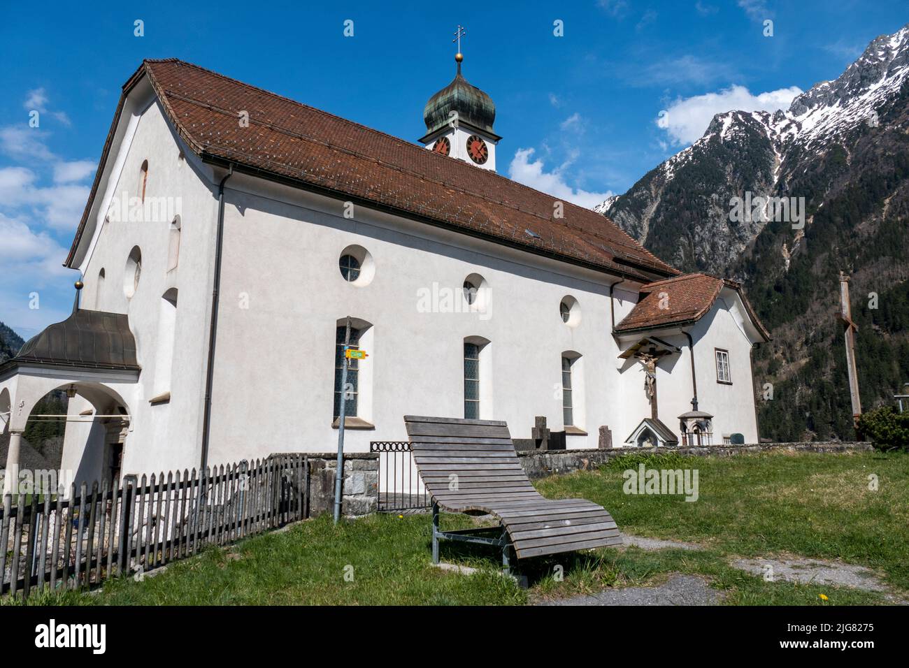 A low angle shot of the Wassen Church St Gallus surrounded by the Alps in Switzerland Stock Photo