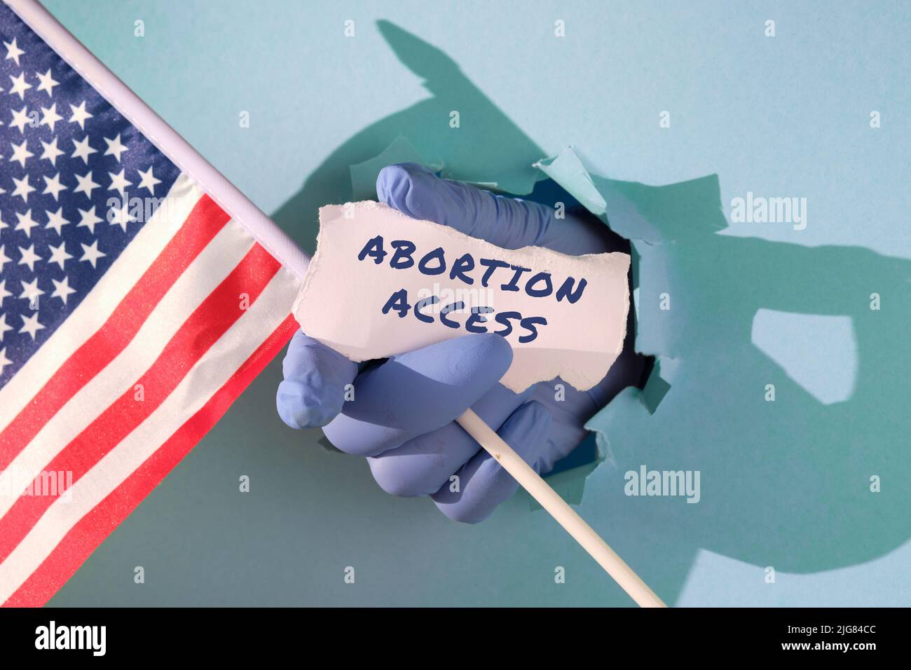 Text Abortion Access on scrap of paper. Medics, doctors hand in glove holding USA american flag and scrap of paper Stock Photo