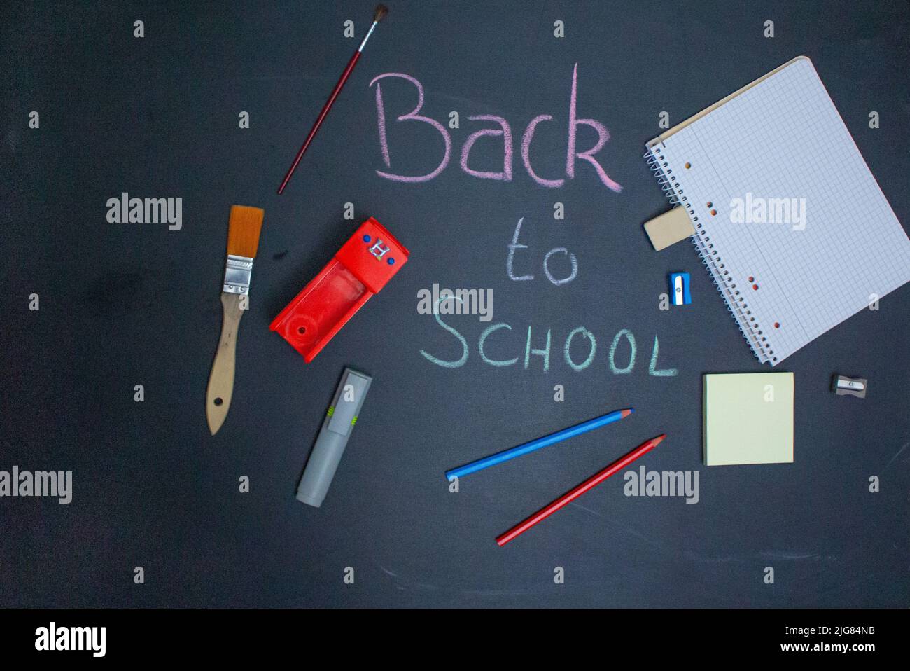 Blackboard with supplies like colored pencils and more school related elements. Stock Photo