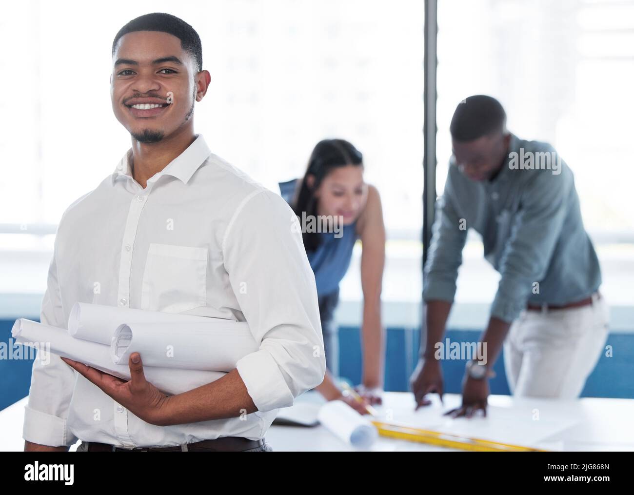 Seeing my plans unfold. Shot of a young male contractor holding a set of blueprints. Stock Photo