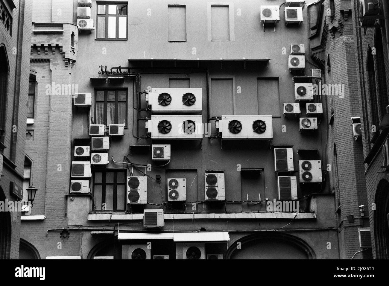 A grayscale shot of outdoor units of split-type air conditioners on the back of a building Stock Photo